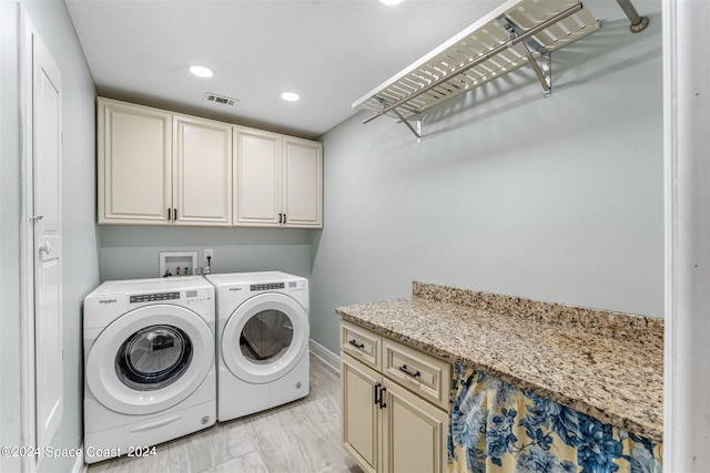 clothes washing area featuring cabinets, light hardwood / wood-style flooring, and washing machine and clothes dryer