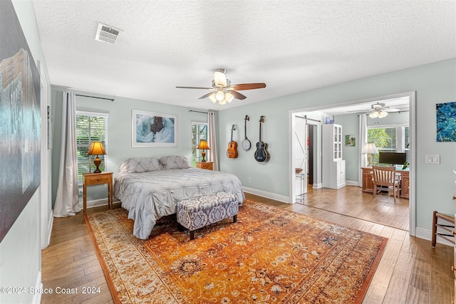 bedroom featuring hardwood / wood-style floors, ceiling fan, and a textured ceiling