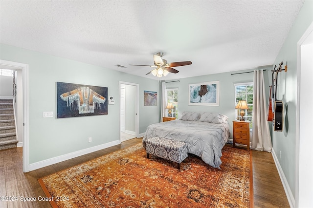 bedroom featuring dark hardwood / wood-style floors, ceiling fan, and a textured ceiling