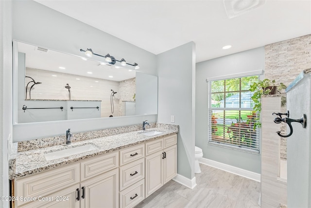 bathroom with toilet, a tile shower, and vanity