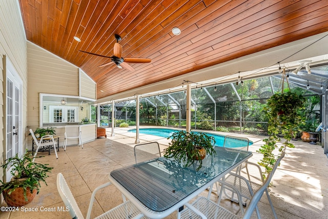 view of pool featuring a patio, glass enclosure, an outdoor bar, and ceiling fan