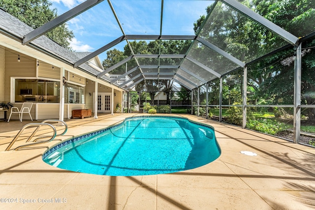 view of pool with french doors, a patio, and glass enclosure