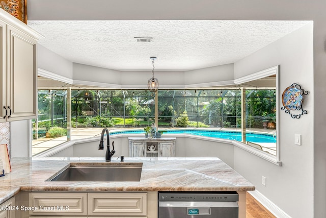 kitchen with light stone countertops, sink, stainless steel dishwasher, cream cabinetry, and light wood-type flooring