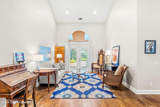 living area featuring hardwood / wood-style flooring, a towering ceiling, and french doors