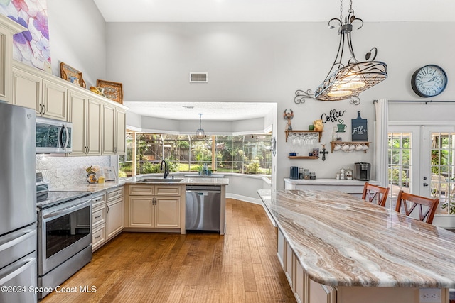 kitchen with light hardwood / wood-style floors, sink, stainless steel appliances, and cream cabinets