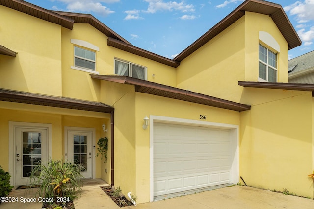 view of front of property with concrete driveway, an attached garage, and stucco siding