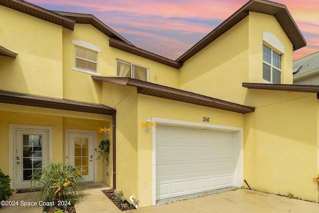 exterior space featuring driveway, an attached garage, and stucco siding