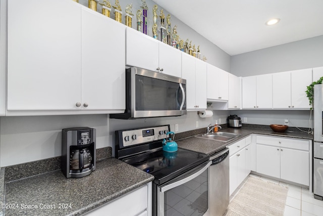 kitchen with stainless steel appliances, dark countertops, white cabinets, and a sink