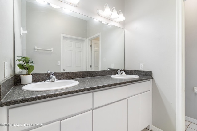 full bathroom with double vanity, a sink, and baseboards