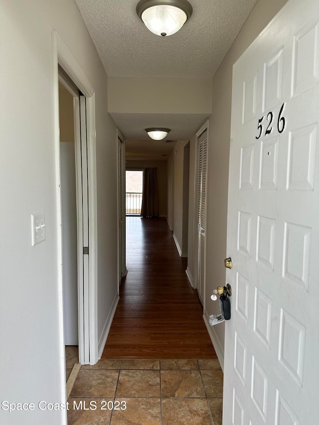 hall with a textured ceiling and hardwood / wood-style floors