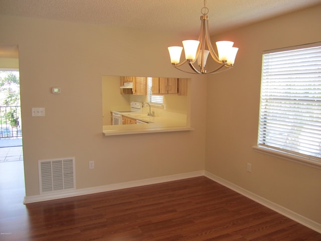 unfurnished room featuring an inviting chandelier, dark hardwood / wood-style flooring, and a textured ceiling