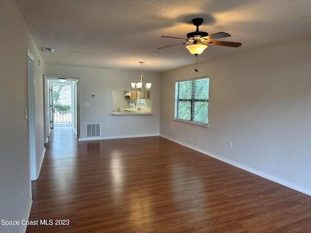 unfurnished living room featuring ceiling fan with notable chandelier, dark hardwood / wood-style flooring, and a textured ceiling