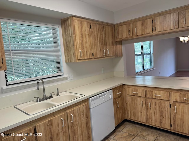 kitchen with a healthy amount of sunlight, light tile patterned flooring, white dishwasher, and sink