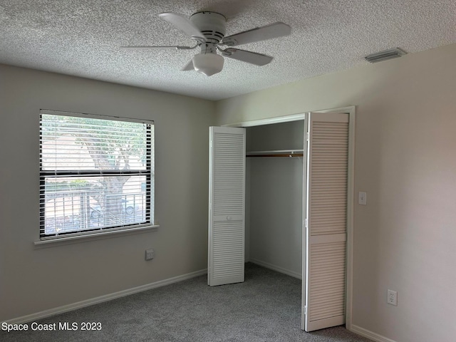 unfurnished bedroom with a closet, ceiling fan, carpet, and a textured ceiling