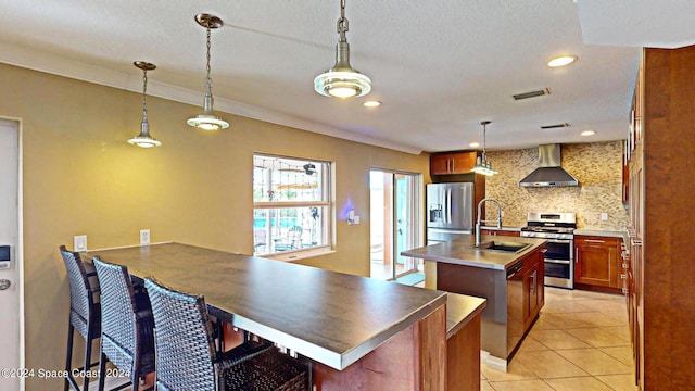 kitchen featuring a center island with sink, tasteful backsplash, appliances with stainless steel finishes, and wall chimney exhaust hood