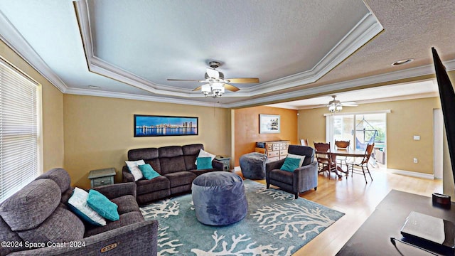 living room with ornamental molding, a textured ceiling, ceiling fan, a raised ceiling, and hardwood / wood-style flooring