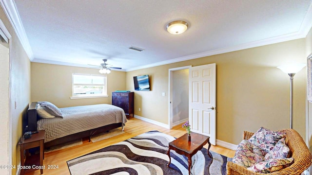 bedroom with a textured ceiling, ceiling fan, ornamental molding, and light wood-type flooring