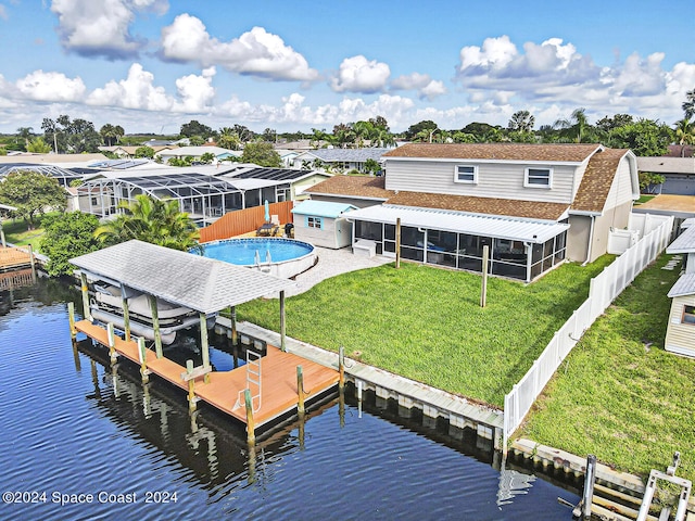 rear view of house with a fenced in pool, glass enclosure, a water view, and a yard