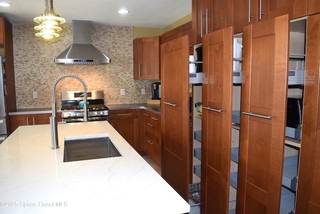 kitchen with gas range, wall chimney range hood, tasteful backsplash, and brown cabinets