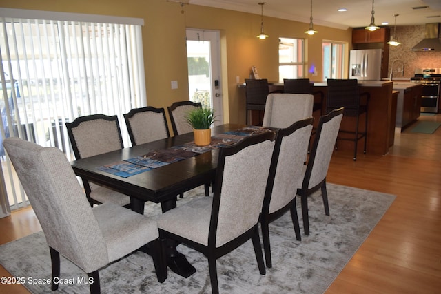 dining area with light wood finished floors, recessed lighting, and crown molding