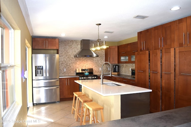 kitchen with brown cabinets, appliances with stainless steel finishes, wall chimney exhaust hood, and light tile patterned flooring