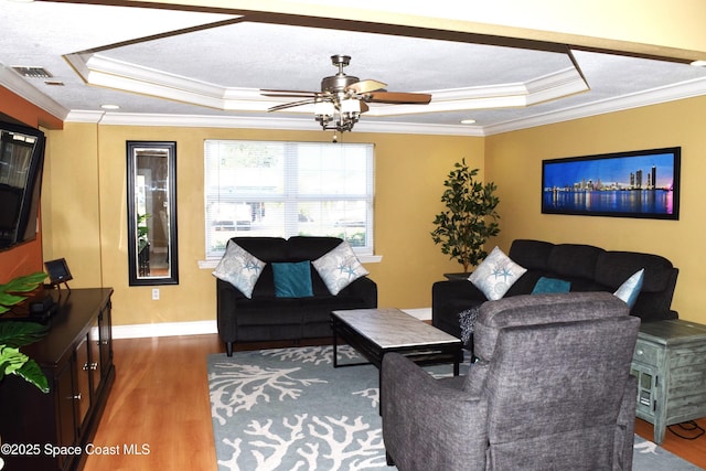 living room with visible vents, a textured ceiling, a tray ceiling, and wood finished floors