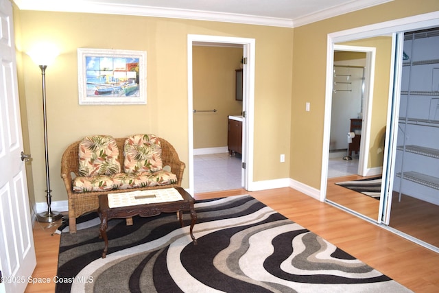 sitting room featuring crown molding, baseboards, and light wood-type flooring