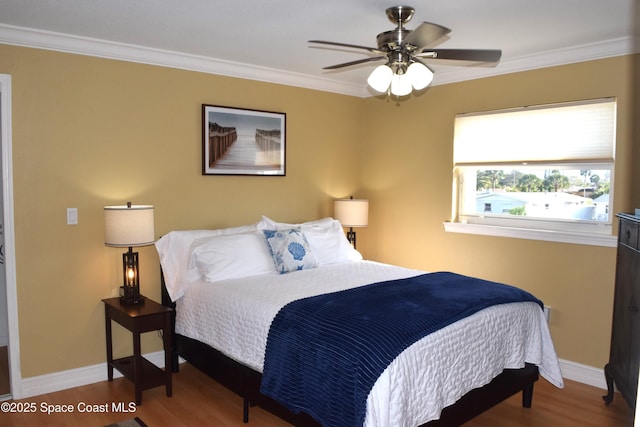 bedroom with ornamental molding, ceiling fan, baseboards, and wood finished floors