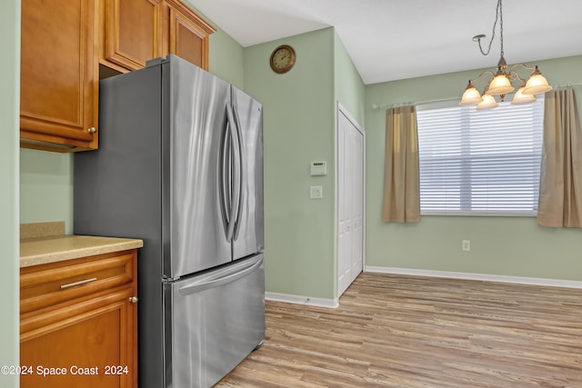 kitchen featuring a notable chandelier, light wood-type flooring, decorative light fixtures, and stainless steel refrigerator