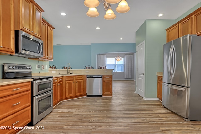 kitchen with light hardwood / wood-style floors, sink, a notable chandelier, hanging light fixtures, and stainless steel appliances