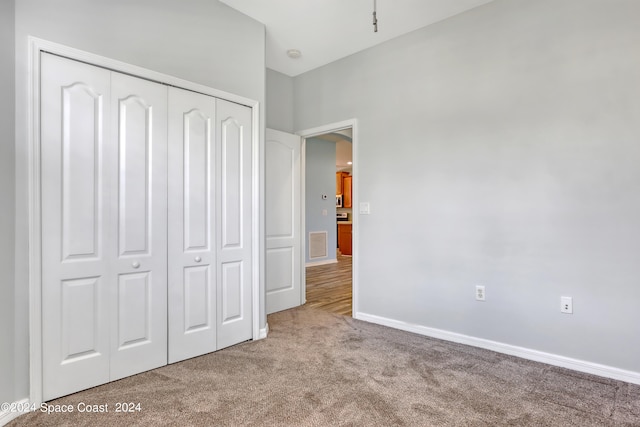 unfurnished bedroom with light colored carpet and a closet