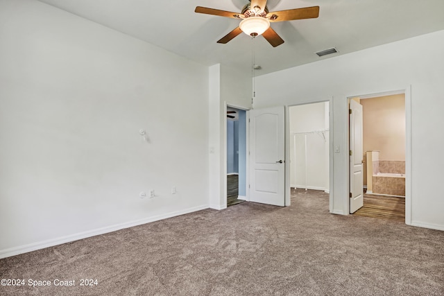 unfurnished bedroom with a spacious closet, a closet, carpet flooring, ceiling fan, and ensuite bathroom