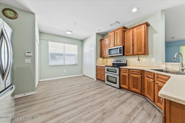 673 Remington Green Dr SE, Palm Bay, FL 32909 - kitchen with visible vents, light countertops, brown cabinetry, light wood finished floors, and stainless steel appliances