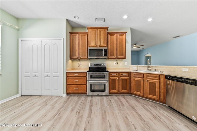 673 Remington Green Dr SE, Palm Bay, FL 32909 - kitchen with visible vents, a sink, appliances with stainless steel finishes, brown cabinetry, and light wood finished floors