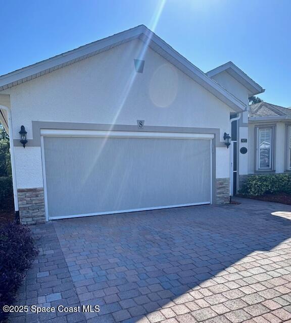 673 Remington Green Dr SE, Palm Bay, FL 32909 - exterior space featuring a garage, stucco siding, stone siding, and decorative driveway