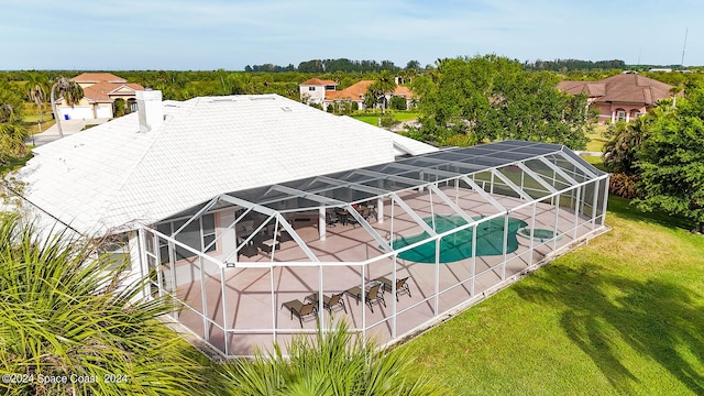 rear view of property featuring glass enclosure, a yard, and a patio area