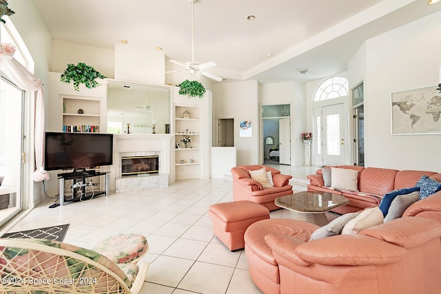 tiled living room with a high ceiling, built in shelves, ceiling fan, and plenty of natural light