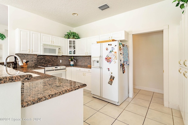 kitchen featuring backsplash, dark stone countertops, white appliances, and white cabinetry