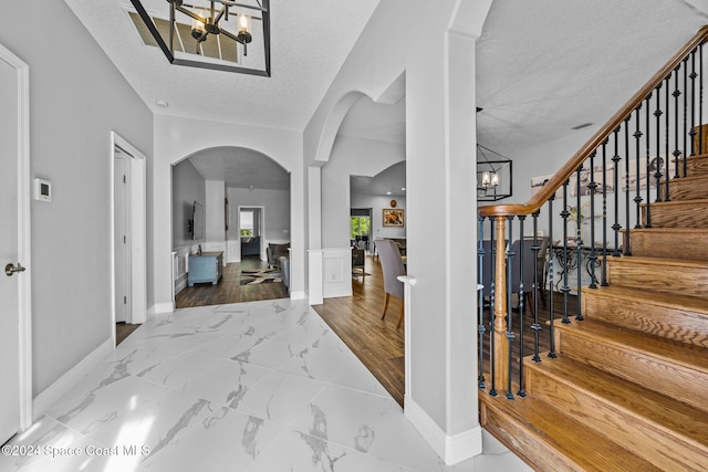 entryway with hardwood / wood-style floors, a textured ceiling, and an inviting chandelier