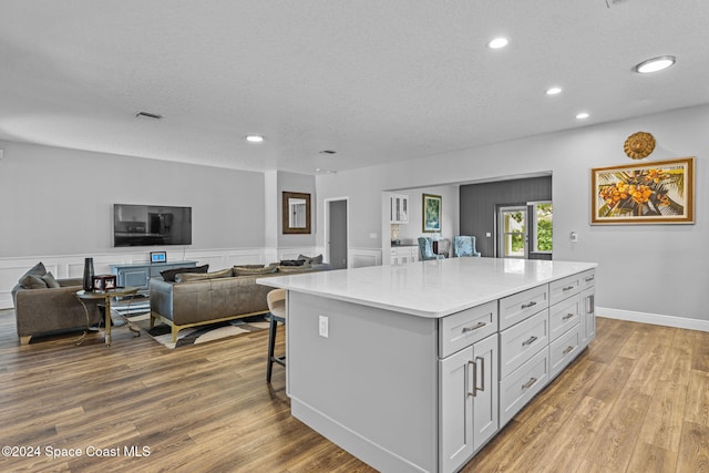 kitchen with a kitchen bar, light wood-type flooring, a textured ceiling, and a kitchen island