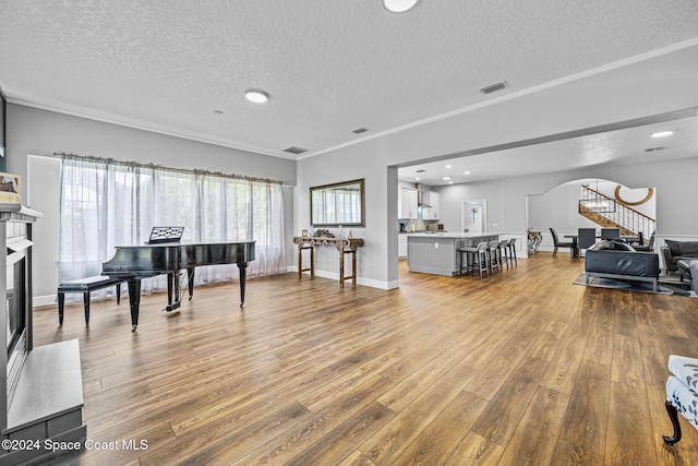 interior space with a textured ceiling, light hardwood / wood-style flooring, and crown molding