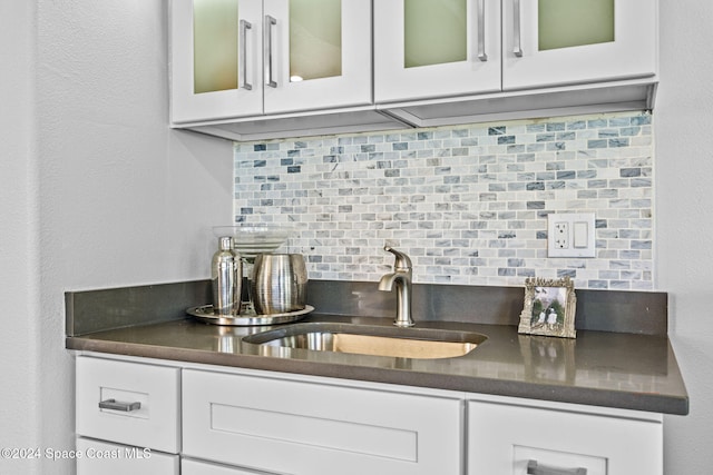 bar featuring white cabinets, sink, and tasteful backsplash