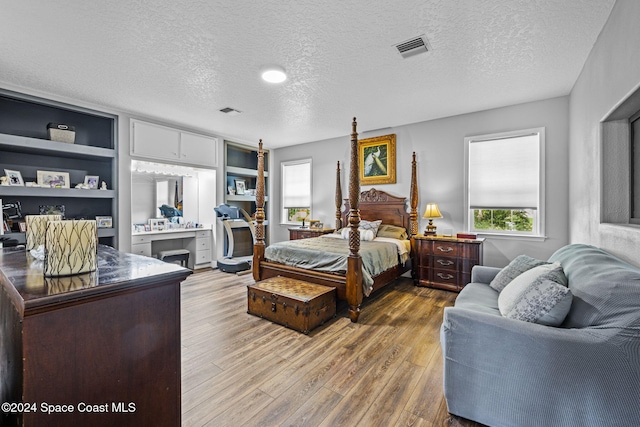 bedroom featuring a textured ceiling, hardwood / wood-style floors, and multiple windows