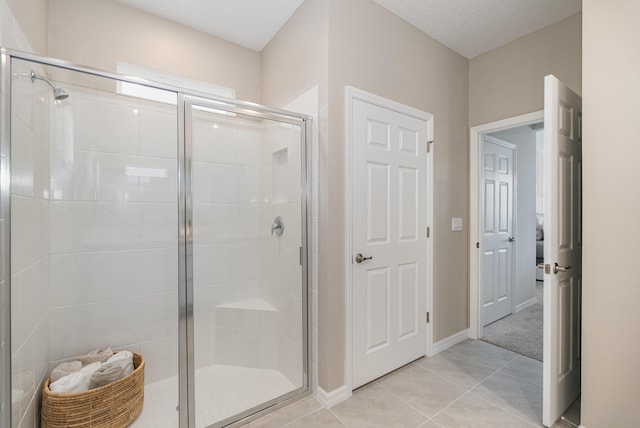 bathroom with a textured ceiling, tile patterned flooring, and an enclosed shower