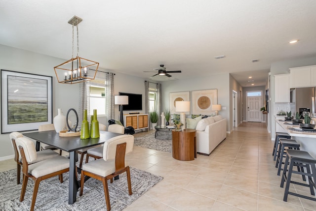 tiled dining room with ceiling fan with notable chandelier