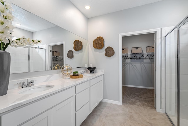 full bath with a sink, double vanity, a stall shower, and a walk in closet