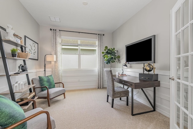 office area with a wainscoted wall, light carpet, and visible vents