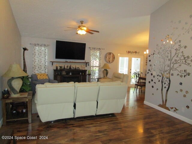 living room featuring ceiling fan with notable chandelier and dark hardwood / wood-style flooring