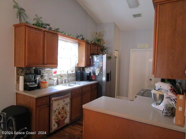 kitchen with stainless steel appliances, tasteful backsplash, sink, dark hardwood / wood-style flooring, and vaulted ceiling