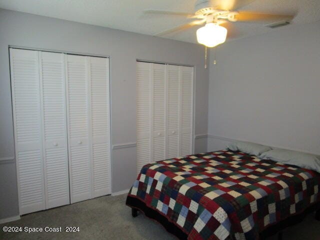 bedroom with ceiling fan, multiple closets, and carpet flooring